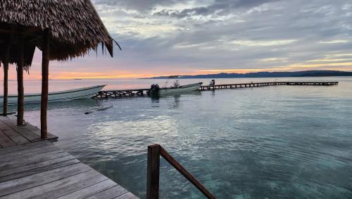 a dock with two boats on the water at sunset at Terimakasih homestay in Pulau Mansuar