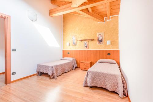 two beds in a room with wooden floors at CROSINA HOLIDAY - Residence Toli in Ledro