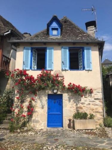 uma pequena casa com uma porta azul e flores em Maison pêcheur sur la Dordogne em Argentat