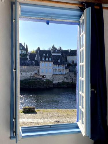 a window with a view of a river and buildings at Maison pêcheur sur la Dordogne in Argentat