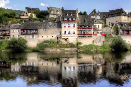 um grupo de edifícios ao lado de uma massa de água em Maison pêcheur sur la Dordogne em Argentat