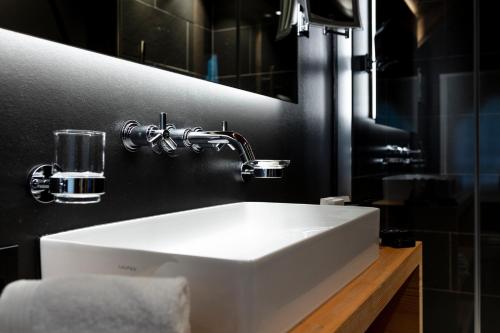 bagno con lavandino bianco e specchio di Hotel-Restaurant Valrose a Gstaad