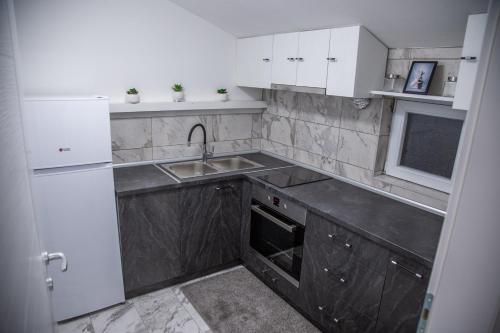 a small kitchen with white cabinets and a sink at Happy in Pirot