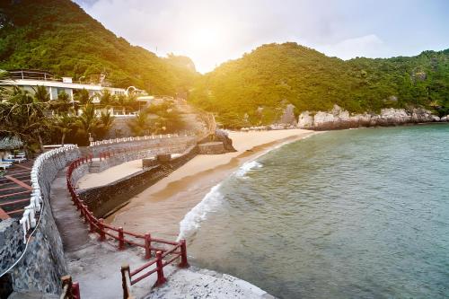 a view of a beach with the ocean and mountains at Quang Thang Cat Ba hotel in Cat Ba