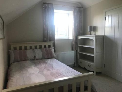 a small bedroom with a bed and a window at Mournes Family Cottage with Hot Tub in Hilltown