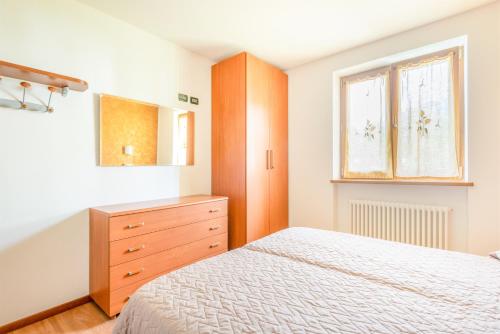 a bedroom with a bed and a dresser and a window at CROSINA HOLIDAY - Residence Toli in Ledro