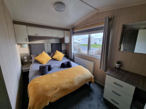a bedroom with a bed with yellow pillows and a window at Seven Sunsets, Padstow in Padstow