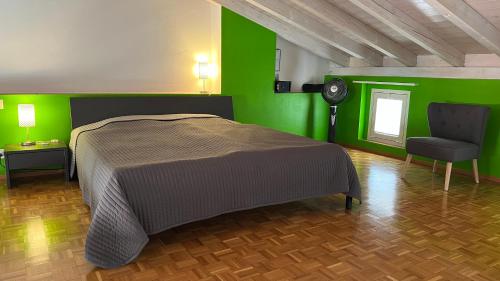 ein grünes Schlafzimmer mit einem Bett und einem Stuhl in der Unterkunft AsconaDolceVita in Ascona