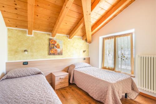 two beds in a room with wooden ceilings at CROSINA HOLIDAY - Residence Toli in Ledro