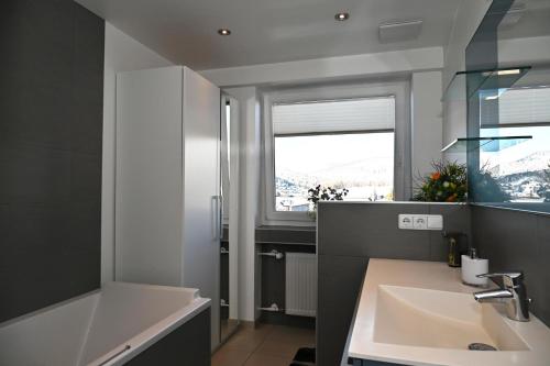 ゼーフェルト・イン・チロルにあるBerghaus Tirol - Luxus Apartementのバスルーム(シンク、バスタブ付)、窓が備わります。