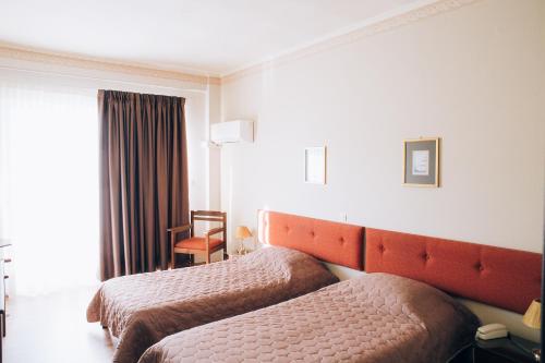 a hotel room with two beds and a window at Tzaki hotel & restaurant Patras in Patra