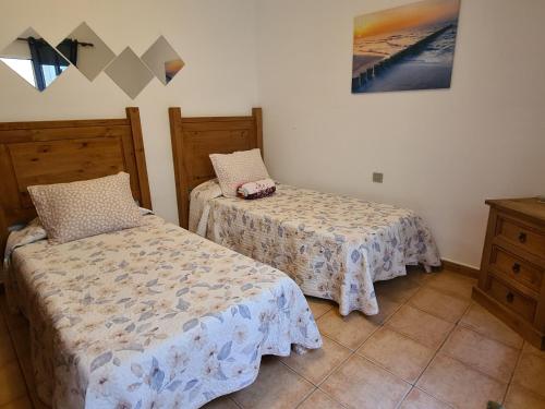 カレタ・デ・ファマラにあるFamara Velaのベッドルーム1室(ベッド2台付)が備わります。壁には絵画が飾られています。