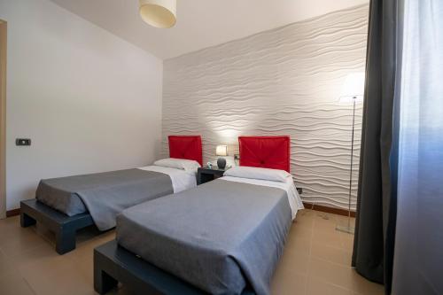 two beds in a room with red pillows at Aparthotel Isabella in Sciacca
