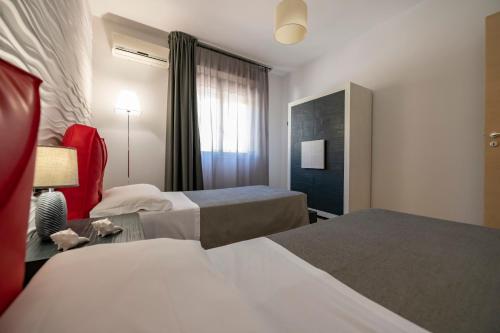a hotel room with two beds and a red chair at Aparthotel Isabella in Sciacca