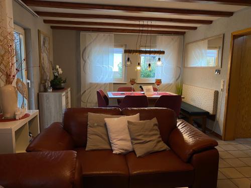 a living room with a brown leather couch and a table at Ferienhaus Sternenhimmel in Thalfang