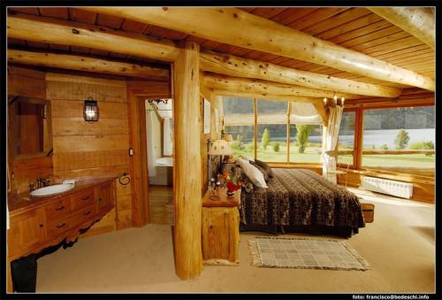 a bedroom in a log cabin with a bed and a sink at Peuma Hue Resort & Cabañas in San Carlos de Bariloche