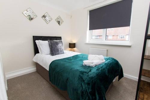 a bedroom with a bed with a green blanket and a window at Spacious-Comfortable-Free Parking-Garden in Nottingham