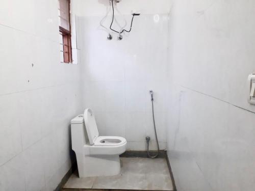 a white bathroom with a toilet and a shower at PEACOCK HILL HOMESTAY in Bhopal