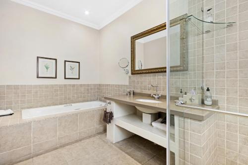 a bathroom with a bath tub and a sink and a bath tubermott at Leighwood Lodge in Johannesburg