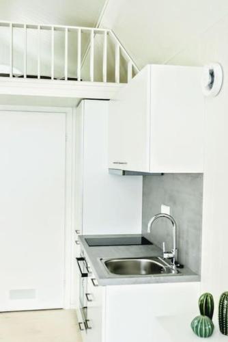 a white kitchen with a sink and a staircase at Charming little country house in central Älmhult in Älmhult