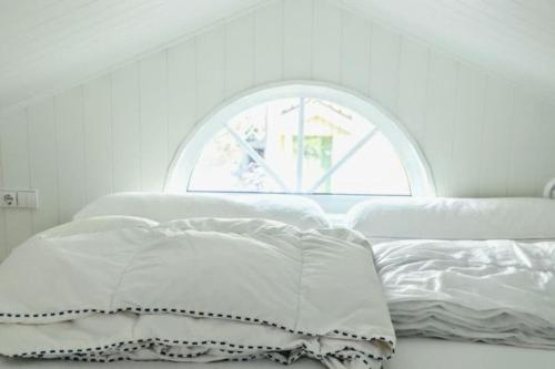 a white bed with a window in a room at Charming little country house in central Älmhult in Älmhult