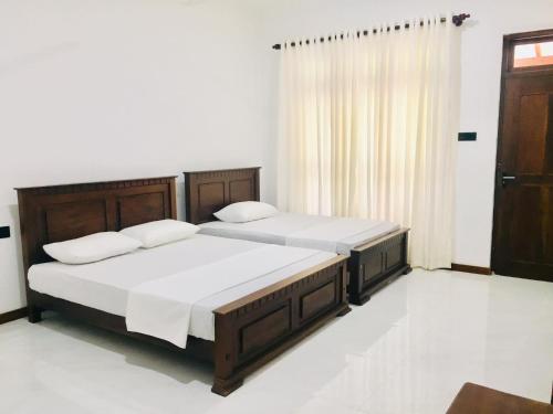 a bedroom with two beds and a window at Swan Lake Habarana in Habarana