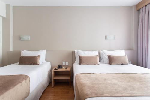a hotel room with two beds and a table at Jandaia Turismo Hotel in Santana do Livramento