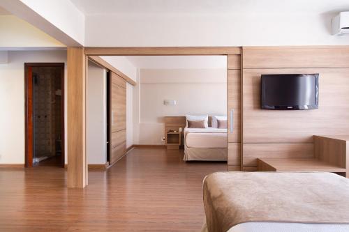 a hotel room with a bed and a tv on a wall at Jandaia Turismo Hotel in Santana do Livramento