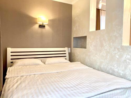 a bedroom with a white bed with a light on the wall at 1-кімн Стильні апартаментами біля Корпусного саду ,Стадіон"Динамо" in Poltava