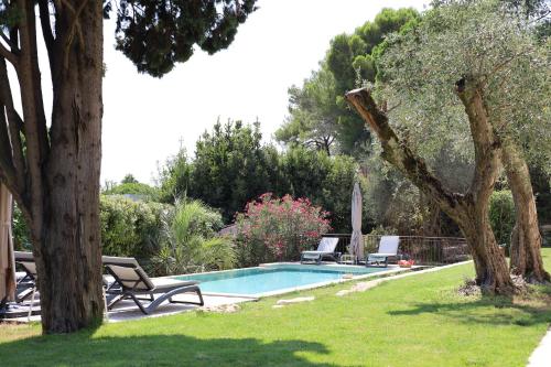 une piscine avec deux chaises et un arbre dans l'établissement L'élégante Bastide en pierre avec vue sur le vieux village de Mougins, à Mougins