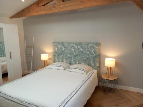 a bedroom with a large white bed with two lamps at Maison Esprit Des Lois in La Brede
