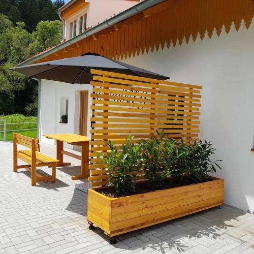 a wooden bench and an umbrella on a patio at Apartmány Rosenberg in Rožmberk nad Vltavou