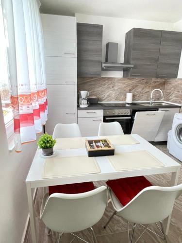 Apartment Marina في أوباتيا: مطبخ بطاولة بيضاء وكراسي بيضاء