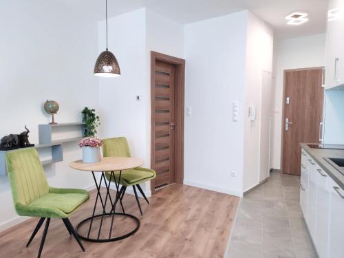 a kitchen with a small table and two green chairs at Spa Residence Carbona Silver Deluxe Apartment in Hévíz