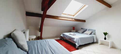 a attic bedroom with two beds and a window at Appartement 3 pièces avec piscine partagée in La Ferté-Gaucher