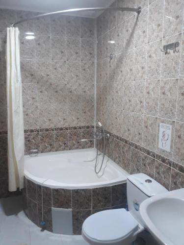 a bathroom with a tub and a toilet and a sink at Guest House Orzu in Khiva