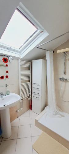 La salle de bains est pourvue d'un lavabo, d'une baignoire et d'une lucarne. dans l'établissement Appartement 3 pièces avec Piscine, à La Ferté-Gaucher