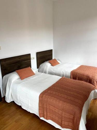 Ortiguero的住宿－La Llamera，白色墙壁客房的两张床
