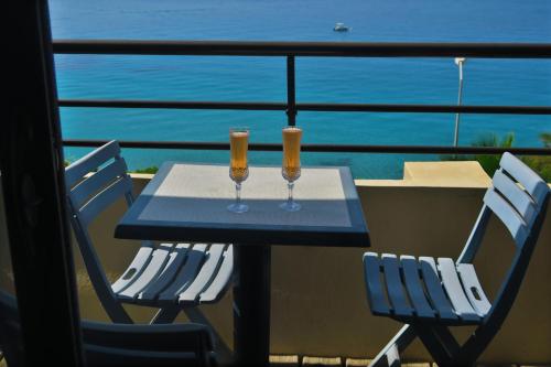 - une table avec deux verres de vin sur le balcon dans l'établissement STUDIO LES CALANQUES, à Ajaccio