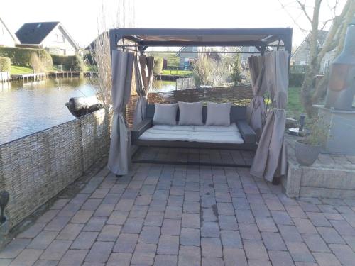 a gazebo with white pillows on a patio at Perle am Ijsselmeer mit eigenem Tretboot in Medemblik