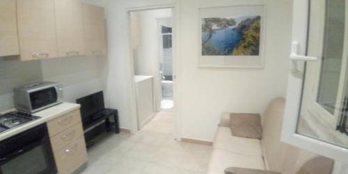 a small white kitchen with a living room with a couch at InBlu in Bari