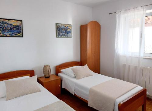 a bedroom with two beds and a window at Apartments Natalia in Supetar