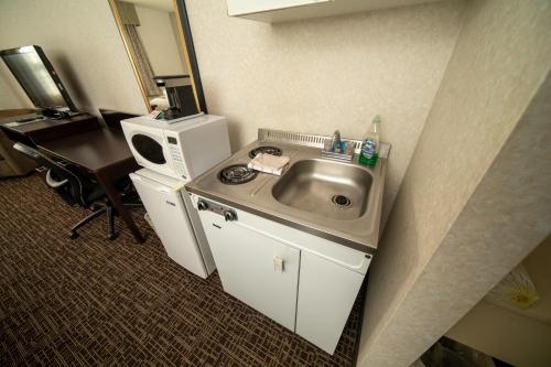 a small kitchen with a sink and a microwave at Coast Fort St John Hotel in Fort Saint John