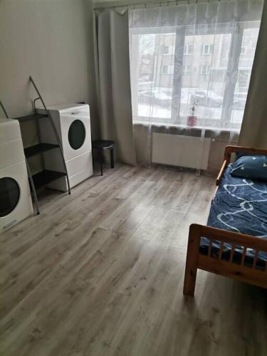 een kamer met een bed, een tv en een raam bij Cozy two-room apartment in Liepāja