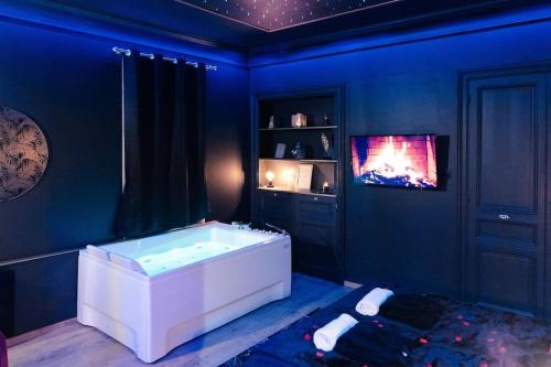 a blue bathroom with a tub and a tv at Rêve d'or in Rouen