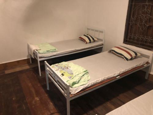 two beds are sitting in a room withthritisthritisthritisthritisthritisthritisthritisthritis at Vernice Backpacker Hostel in Vientiane