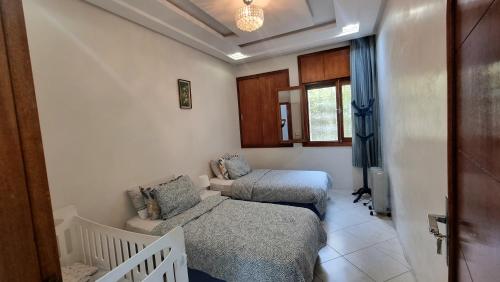 カサブランカにあるLuxury Family House with Garden View Casablancaのベッド2台と椅子が備わる小さな客室です。