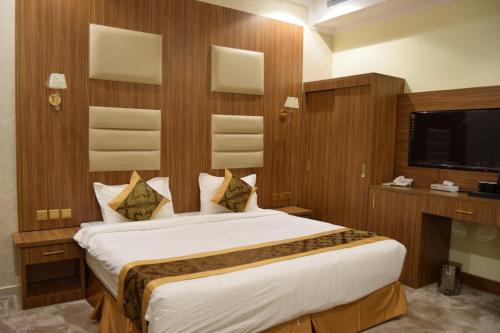 una camera con un grande letto e una TV di فندق اللؤلؤة الذهبي a Sīdī Ḩamzah