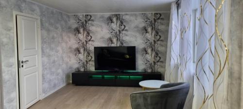 a living room with a tv and a chair at Holiday apartment in Kleppstad