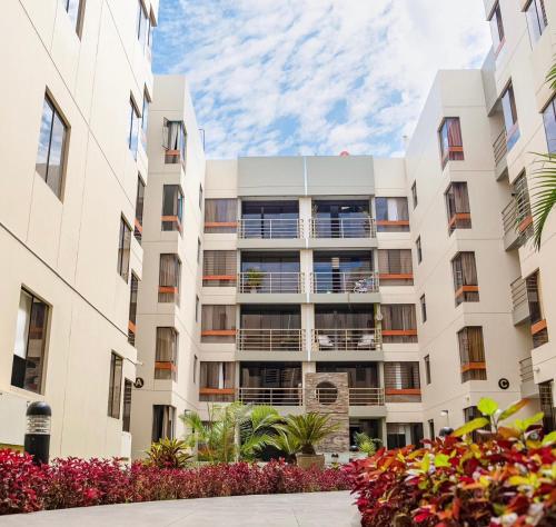 ein Apartmenthaus mit Blumen davor in der Unterkunft Hermoso Departamento dentro de un Condominio in Chiclayo